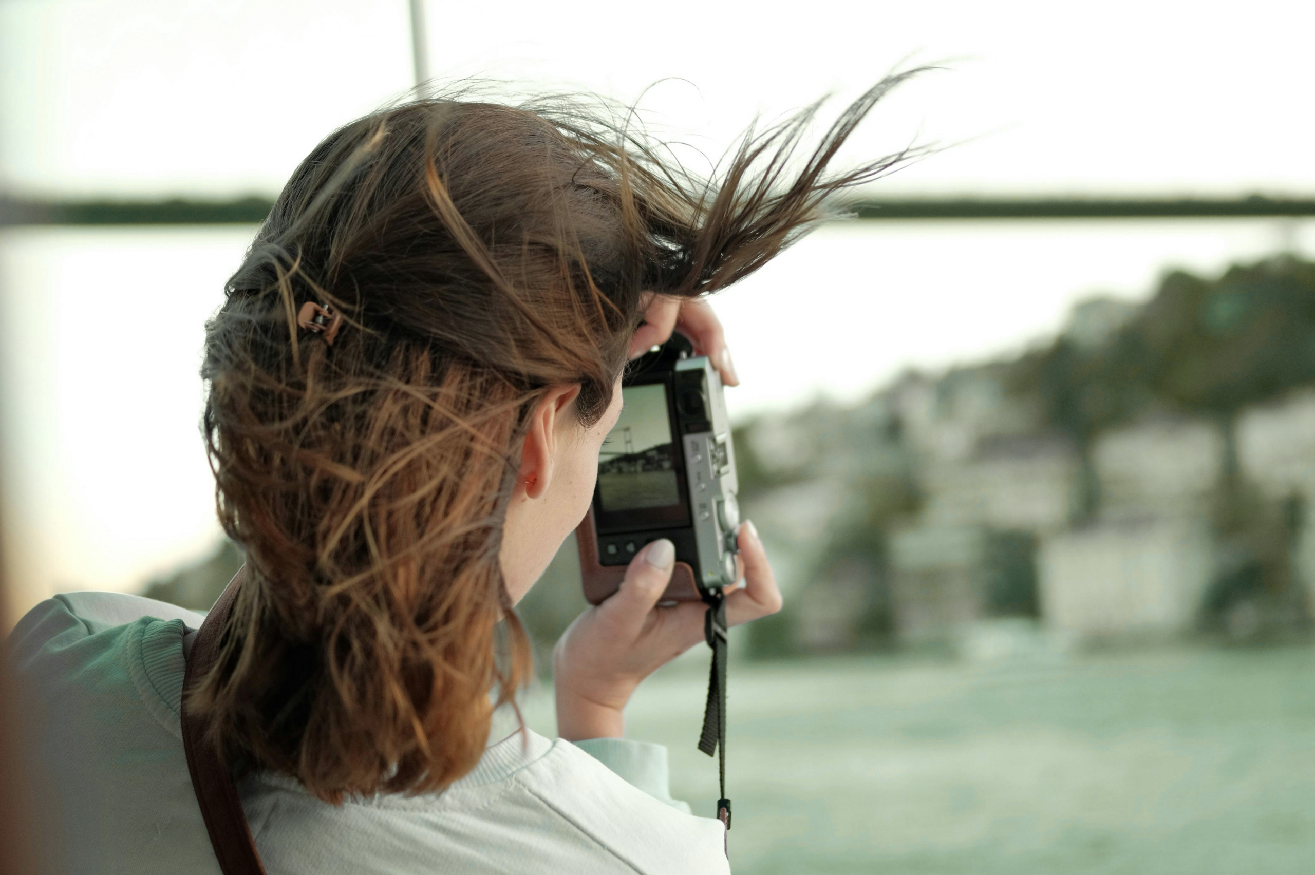 A woman taking a photo of buildings by the sea